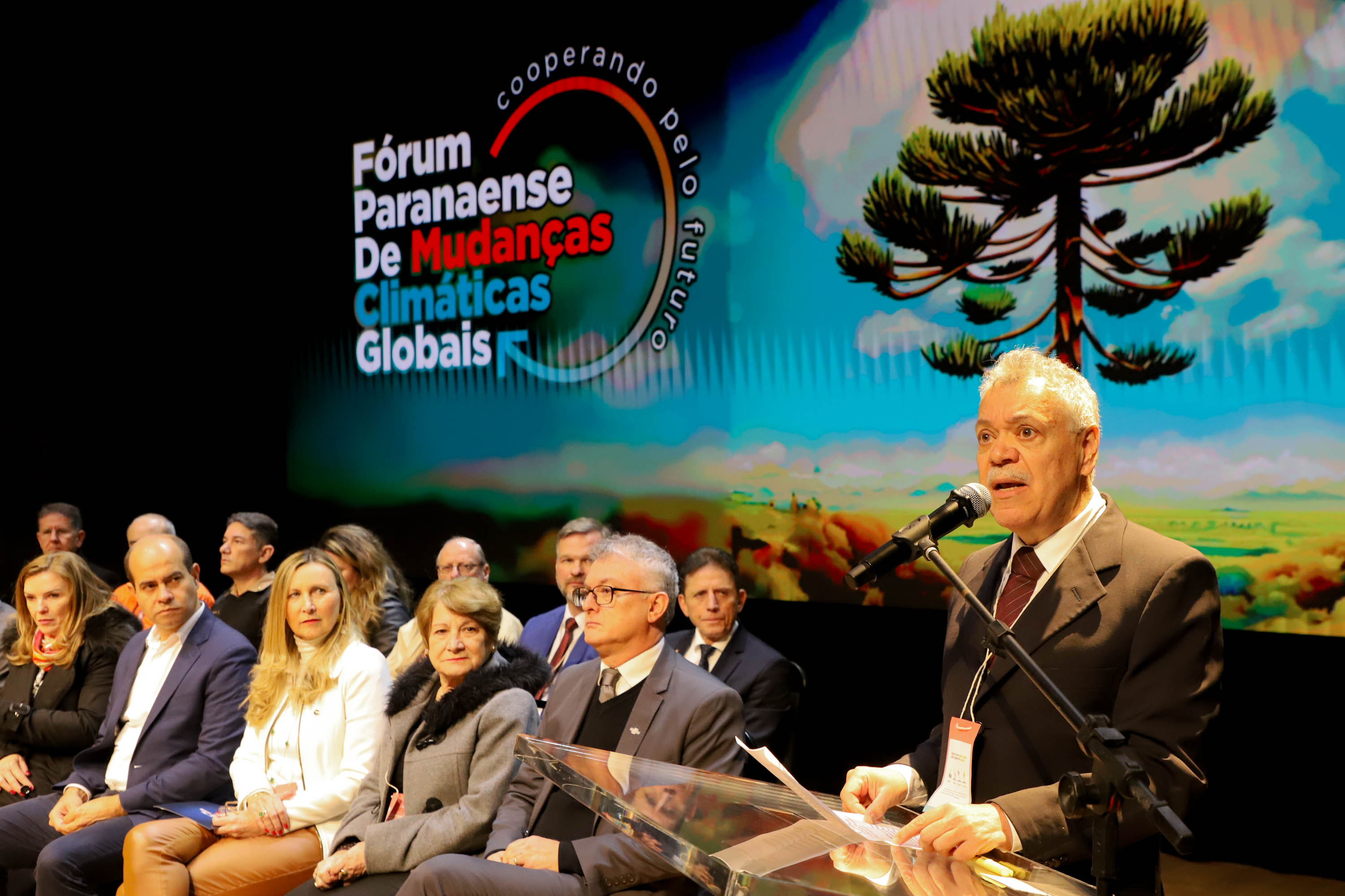 Apresentação fórum Paranaense de Mudanças Climáticas com membros assentados e apresentador discursando