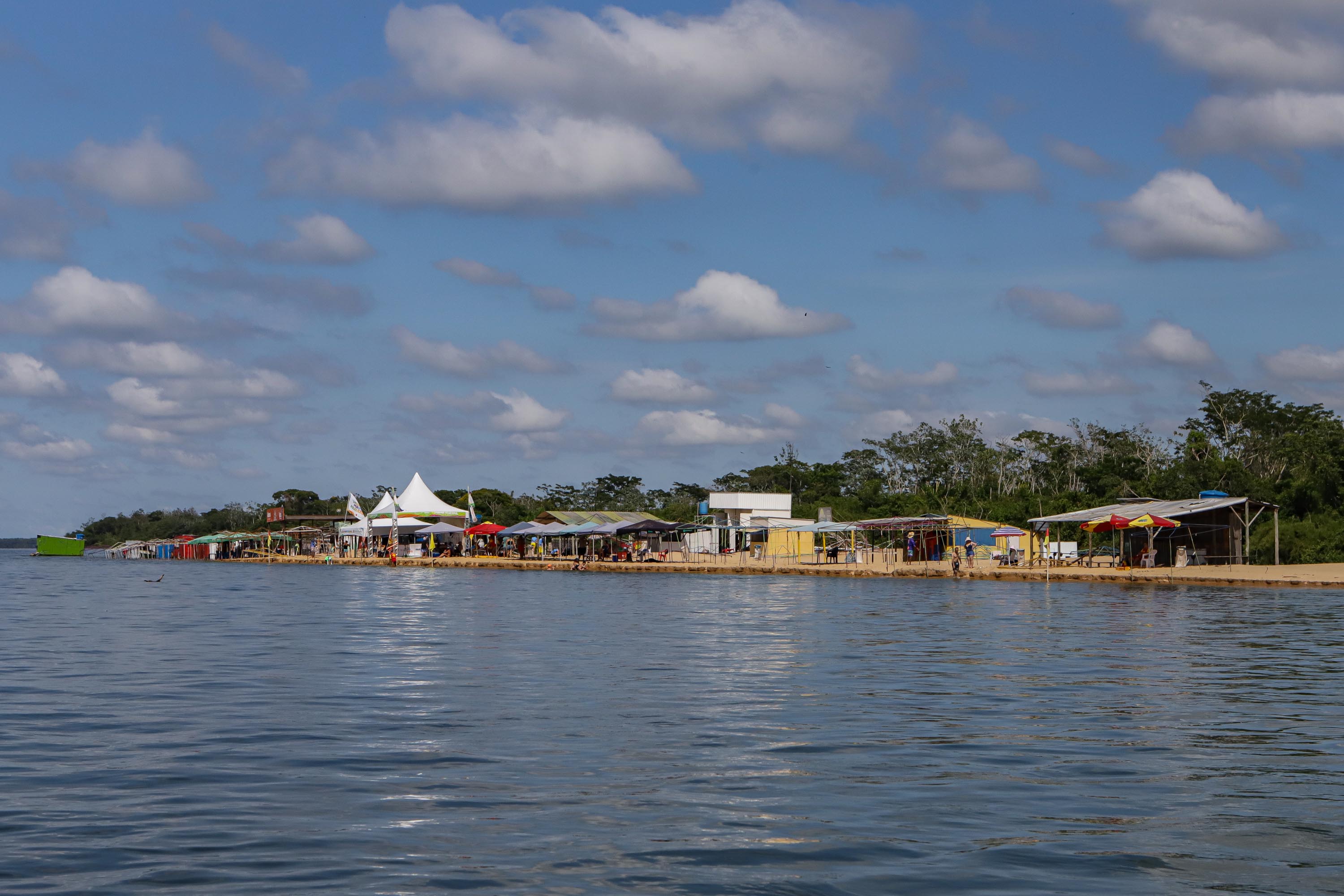 Margem do Rio Paraná com barracas próximas ao rio.
