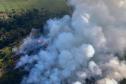 IMAGEM AÉREA MOSTRANDO ÁREA DE DESMATAMENTO COM INTENSA FUMAÇA