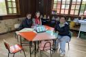 Foto da mestranda sentada com professoras na mesa