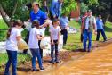 Crianças supervisionadas por adultos soltando os peixes na água