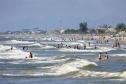 Banhistas em meio a praia e o mar do Paraná