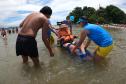 Voluntários transportando uma idosa sobre o mar