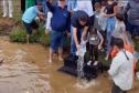 Foto de autoridades e crianças durante soltura de peixes