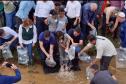 Foto de autoridades e crianças durante soltura de peixes