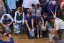 Foto de autoridades e crianças durante soltura de peixes