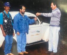 Foto de três servidores do IAT em frente à carro
