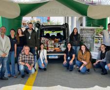 Equipe do IAT de 13 pessoas posando para foto com material do estande ao fundo
