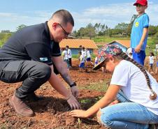 Servidor do IAT ensinando uma criança a plantar uma muda