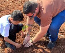 Servidor do IAT ensinando uma criança a plantar uma muda