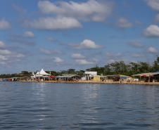 Margem do Rio Paraná com barracas próximas ao rio.
