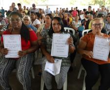 Beneficiárias posando para foto com o título de regularização em mãos