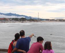 Família prestigiando um surfista surfando
