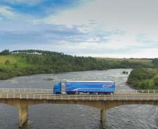 Caminhão da DAF passando por uma ponte com a natureza paranaense ao fundo