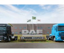 Fachada da DAF com dois caminhões dos lados da placa de identificação