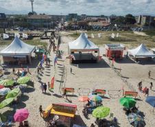 Praia com varios banhistas em torno de barracas e guarda-sois