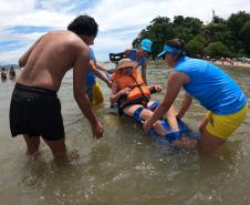 Voluntários transportando uma idosa sobre o mar
