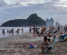 Banhistas apreciando a praia com prédios e um morro ao fundo