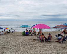 Banhistas apreciando a praia com o mar ao fundo