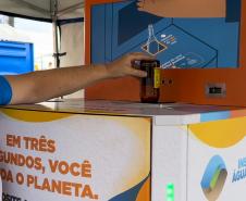 Foto de pessoa depositando garrafa na máquina de reciclagem