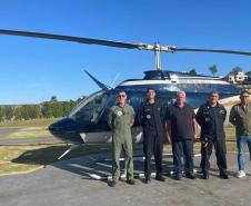 Agentes fiscalizadores posando para foto com um helicóptero ao fundo