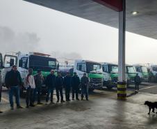 VOLUNTÁRIOS POSANDO COM CAMINHÕES AO FUNDO