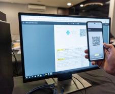 INIDIVÍDUO LENDO UM QR CODE NO COMPUTADOR COM SEU CELULAR