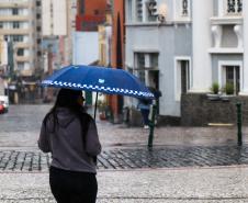 TRANSEUNTE SE PROTEGENDO DA CHUVA NO LARGO DA ORDEM