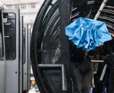 TRANSEUNTE SE PROTEGENDO DA CHUVA FRENTE A ESTAÇÃO TUBO