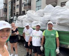 Foto de pessoas em frente a caminhão de lixo