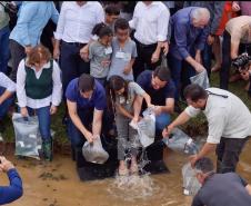 Foto de autoridades e crianças durante soltura de peixes