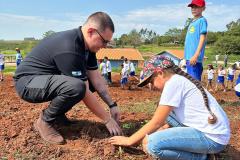 Agente do IAT orientando uma criança a plantar