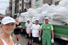 Foto de pessoas em frente a caminhão de lixo