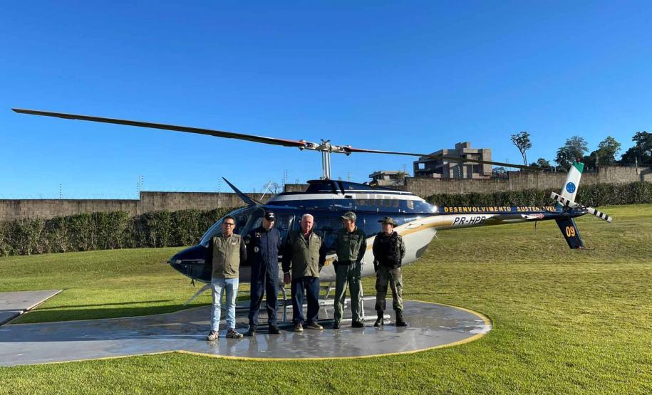EQUIPE DE SERVIDORES POSANDO A FRENTE DO HELICOPTERO UTILIZADO PARA FISCALIZAÇÃO E MONITORAMENT