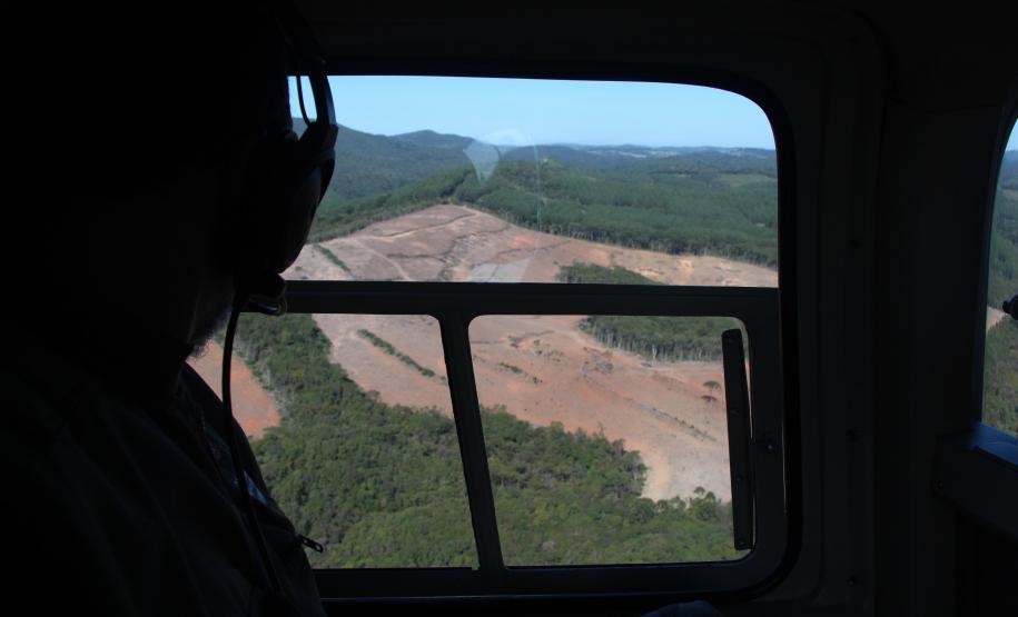 Imagem de dentro do helicoptero para fora, focado na área desmatada