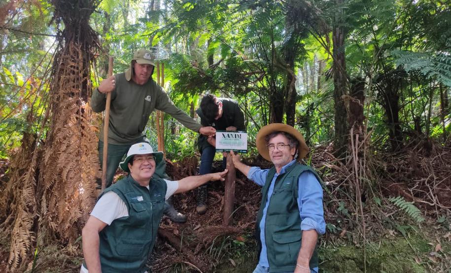 Foto de trabalhadores em frente à placa