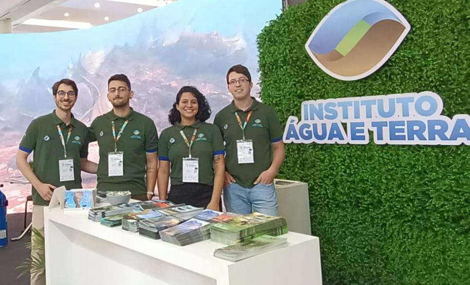 Foto de funcionários do IAT em frente ao estande do instituto