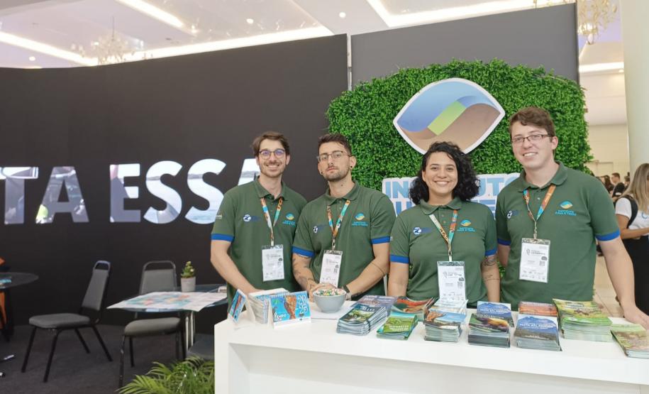 Foto de funcionários do IAT em frente ao estande do instituto