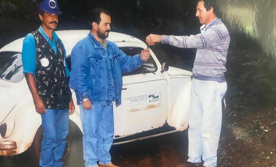 Foto de três servidores do IAT em frente à carro