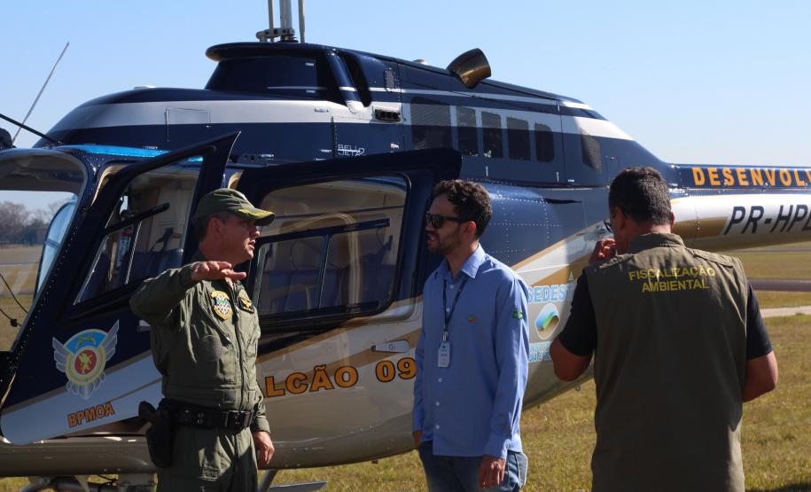equipe PM e IAT próximos ao helicoptero pousado no chão