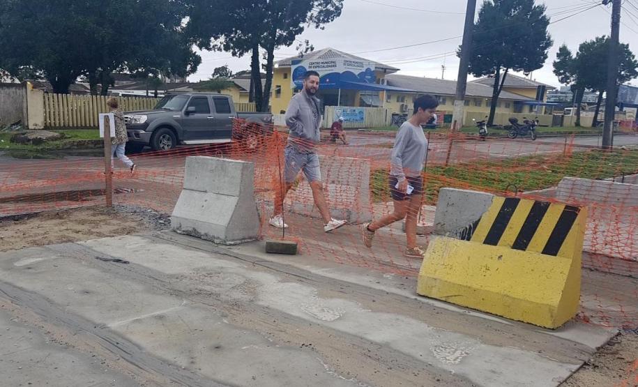 Foto de pedestres cruzando obra de microdrenagem
