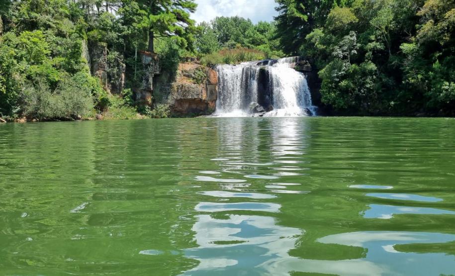 Foto de superfície de rio com um cachoeira ao fundo