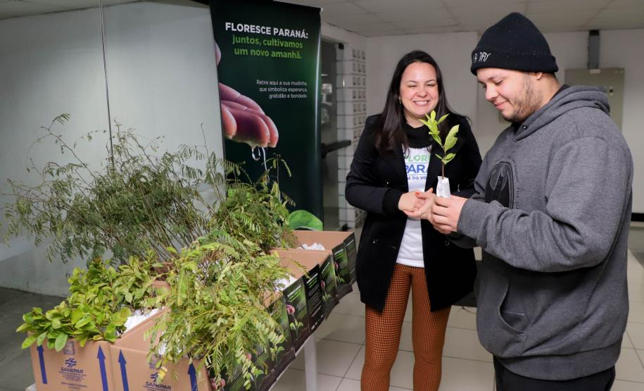Representantes do IAT posando para foto com civis a frente do banner "Florescer Paraná"