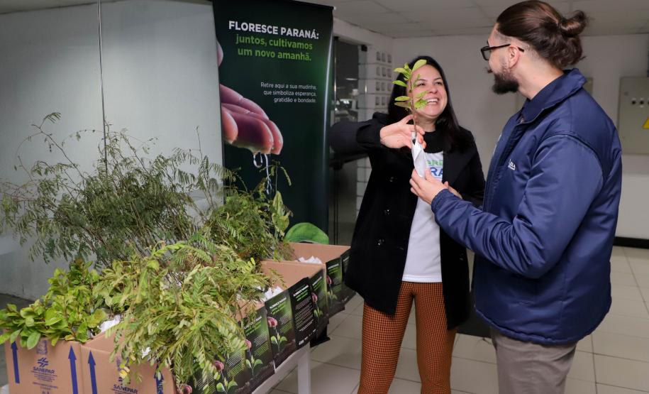 Representantes do IAT posando para foto com civis a frente do banner "Florescer Paraná"