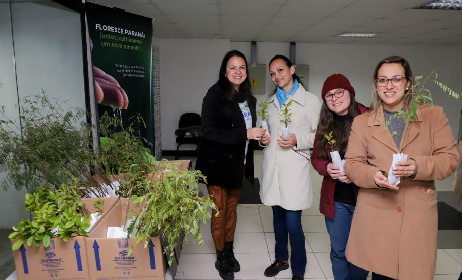Equipe do IAT posando para foto com civis com mudas em mãos