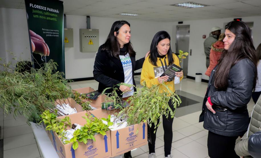 Representantes do IAT posando para foto com civis a frente do banner "Florescer Paraná"