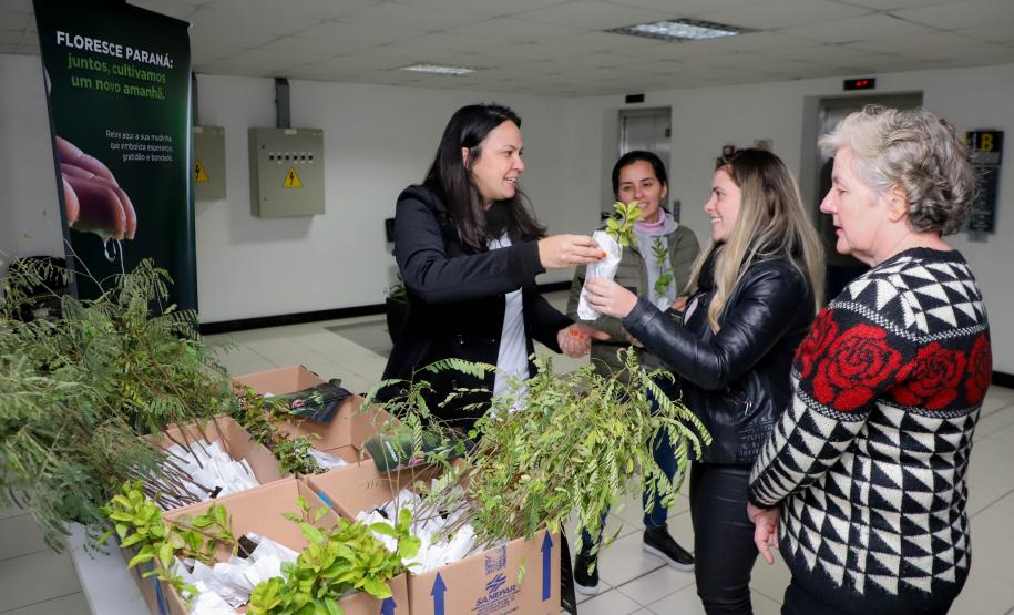 Representantes do IAT posando para foto com civis a frente do banner "Florescer Paraná"