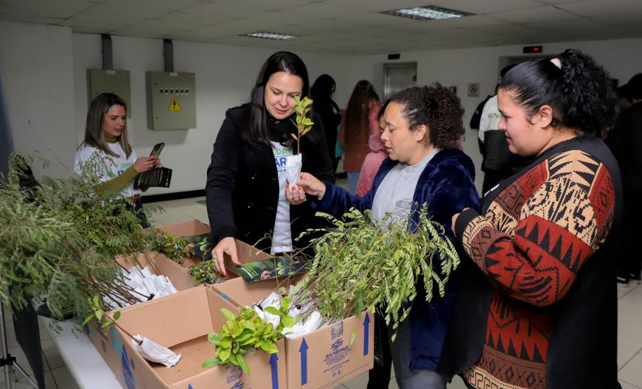 Representantes do IAT posando para foto com civis a frente do banner "Florescer Paraná"
