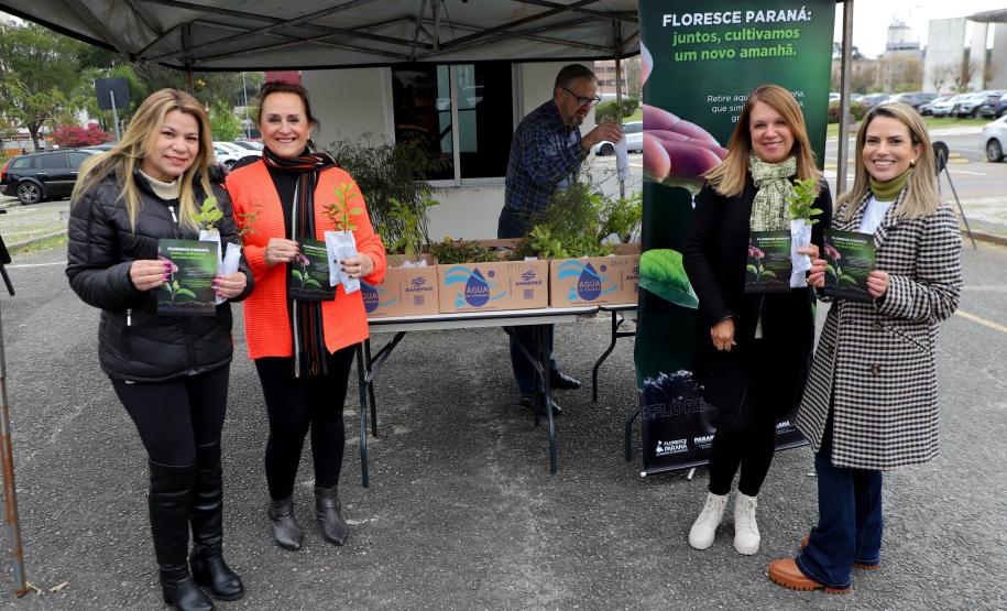 Representantes do IAT posando para foto com civis a frente do banner "Florescer Paraná"