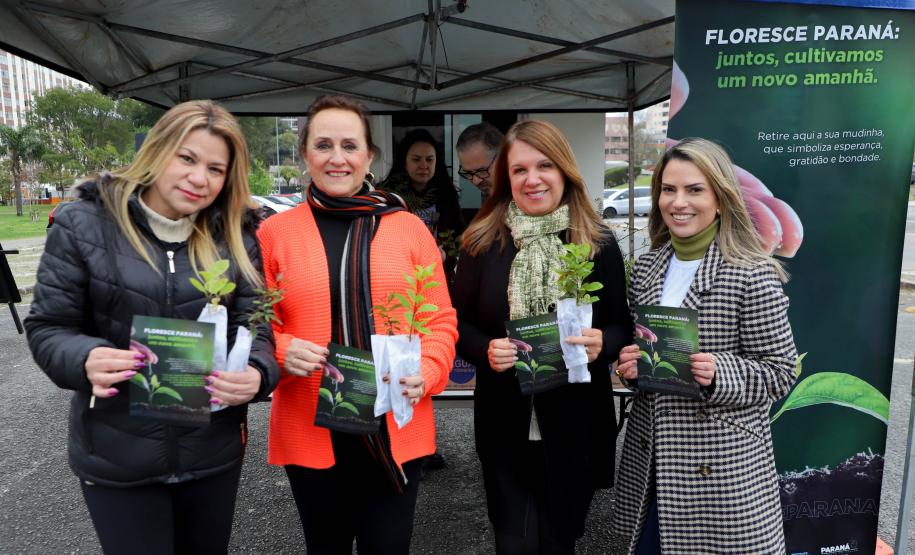Representantes do IAT posando para foto com civis a frente do banner "Florescer Paraná"